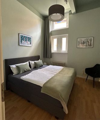 Premium Kingsize Suite - Schlafzimmer mit Doppelbett, großem Fenster und Sessel